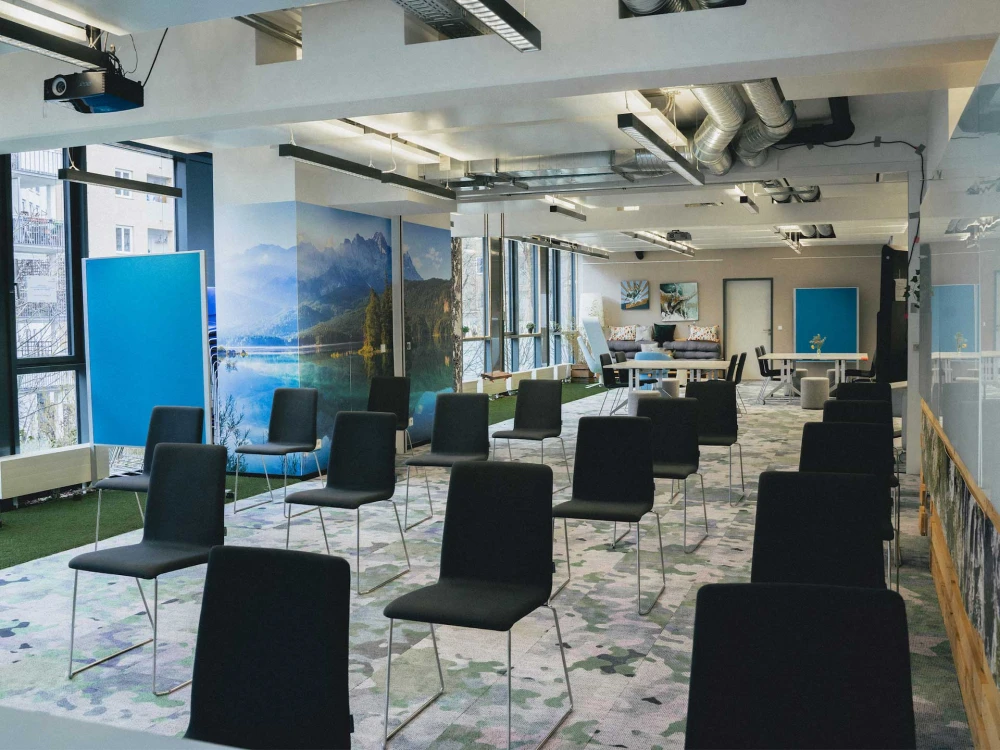 Moderner, lichtdurchfluteter Konferenzraum mit flexibler Bestuhlung, Alpen-Wandmotiv, kreativen Arbeitsbereichen und industriellen Designelementen.