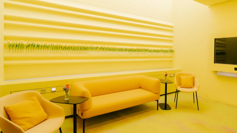 Heller und freundlich gestalteter Konferenz- und Besprechungsraum im Smartvillage Bogenhausen, ausgestattet mit modernen, ergonomischen Stühlen, einem bequemen gelben Sofa und kreativen Wanddekorationen