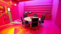 Moderner Meetingraum mit intensiver pinker Farbgestaltung, rundem Konferenztisch mit schwarzen Lederstühlen und auffälliger Graffiti-Wand mit leuchtenden Farben