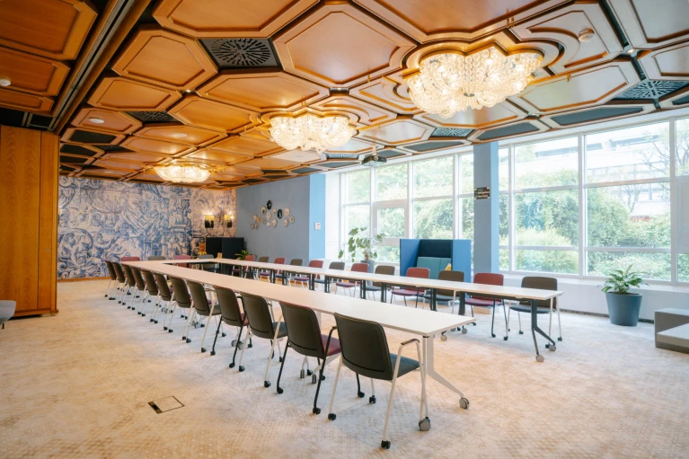 Eleganter Tagungsraum mit Kronleuchtern, Holzdecke und großer Fensterfront für eine helle Atmosphäre