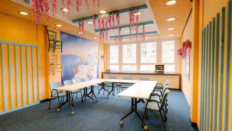 Meetingraum mit mediterranem Flair, blauen Akzenten, Wandkunst und hängenden Blumen für eine inspirierende Atmosphäre