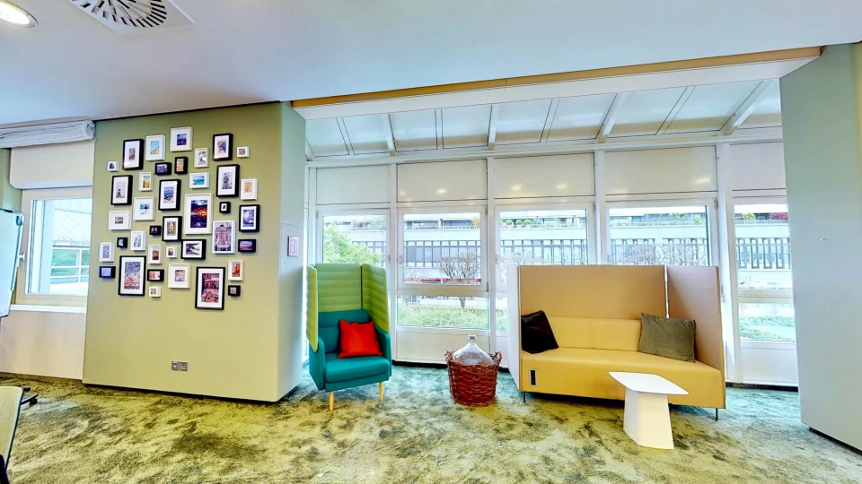 Bildergalerie an grüner Wand mit Lounge-Sesseln und Tageslicht im Workshopraum Smartvillage