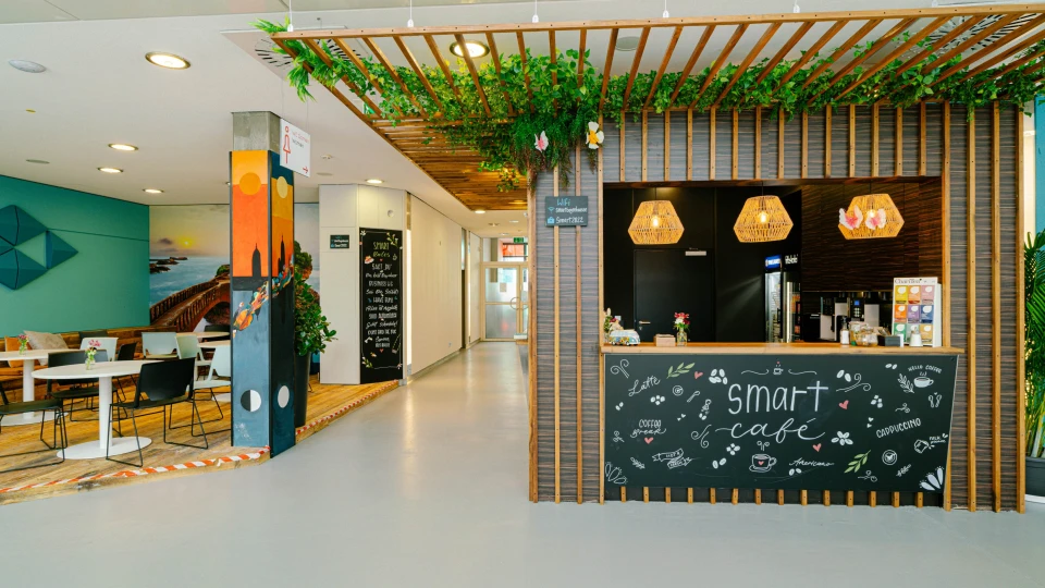 Gemütliches Café mit Holzverkleidung, grüner Decke und Smart-Café-Tafel im modernen Workspace